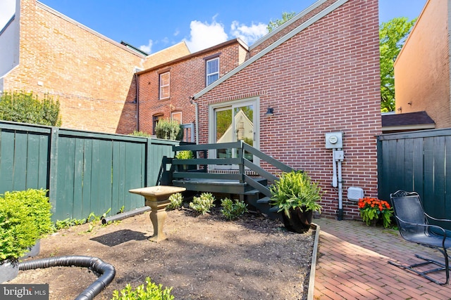 rear view of house with brick siding, a fenced backyard, and a patio
