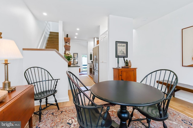 dining room featuring light wood finished floors, stairway, baseboards, and recessed lighting