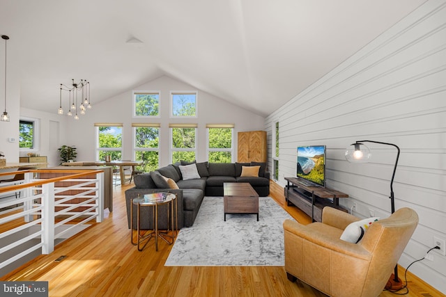 living area featuring a chandelier, wood finished floors, wooden walls, and high vaulted ceiling