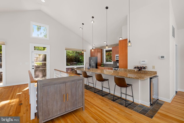 kitchen with visible vents, a peninsula, beverage cooler, high vaulted ceiling, and refrigerator with ice dispenser