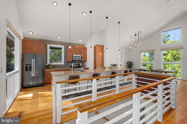 2621 S Arlington Ridge Rd, Arlington, VA 22202 - kitchen with high vaulted ceiling, brown cabinets, light wood-style flooring, hanging light fixtures, and stainless steel appliances