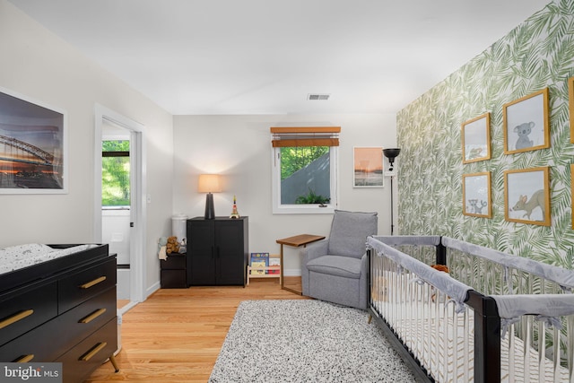 bedroom featuring wallpapered walls, visible vents, multiple windows, and light wood-style flooring