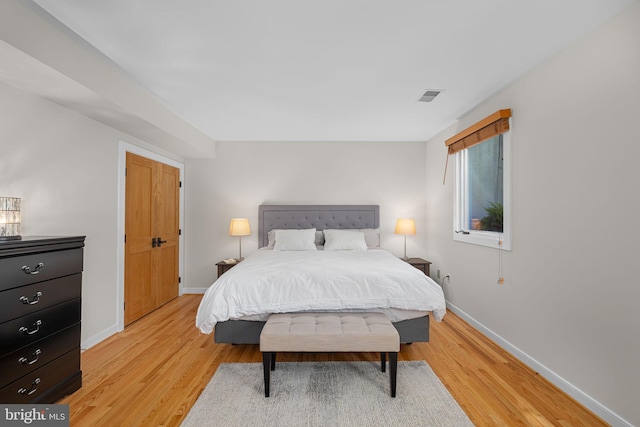 bedroom featuring baseboards, visible vents, and light wood finished floors