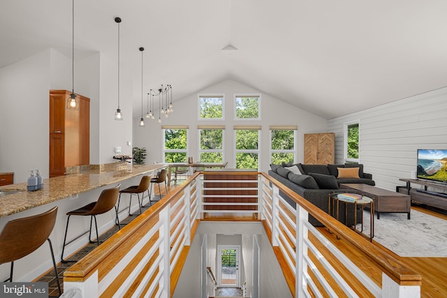 living area with high vaulted ceiling, wood walls, and a healthy amount of sunlight
