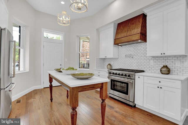kitchen with appliances with stainless steel finishes, decorative backsplash, a notable chandelier, and custom range hood
