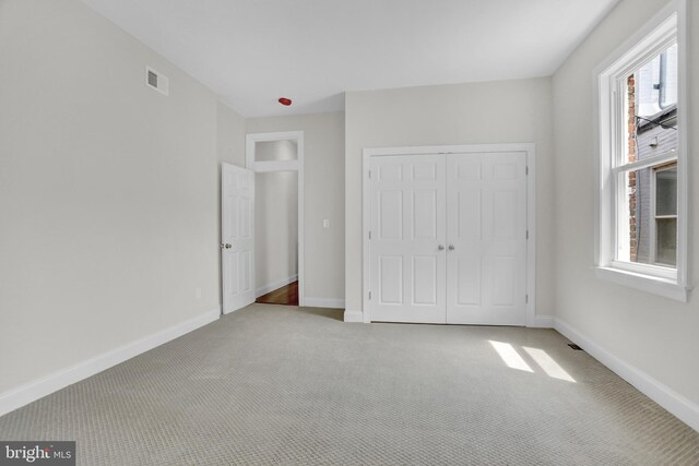 unfurnished bedroom featuring visible vents, baseboards, carpet flooring, and a closet