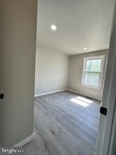 unfurnished room featuring recessed lighting, wood finished floors, and baseboards