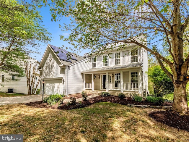 traditional-style house with roof mounted solar panels, driveway, and a porch