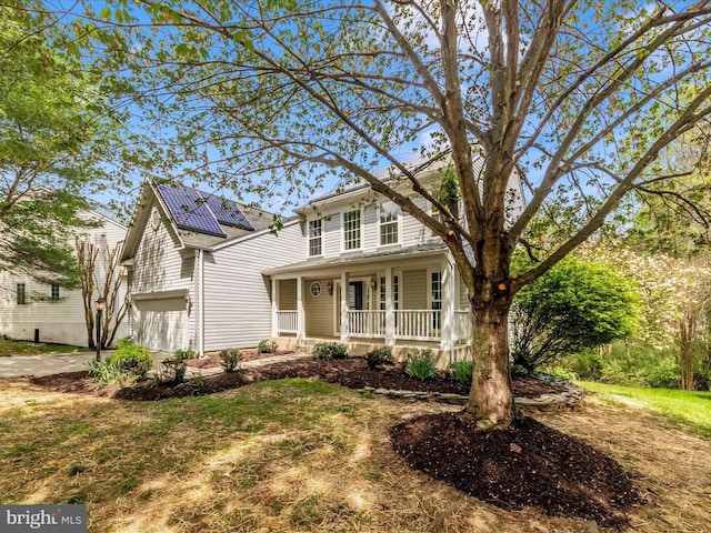 traditional-style house featuring a garage, a porch, and concrete driveway