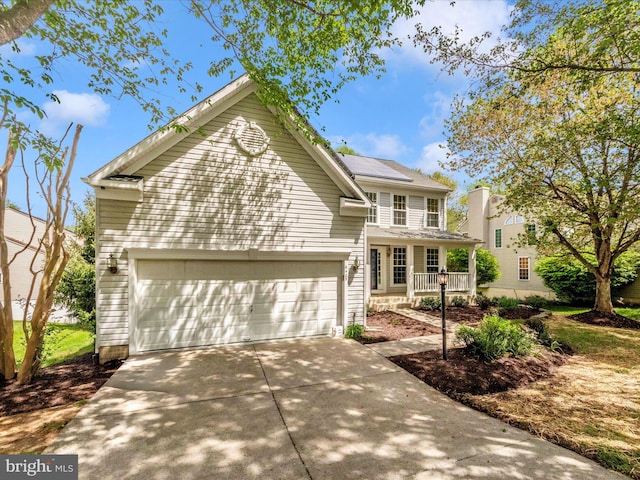 traditional home featuring roof mounted solar panels, driveway, an attached garage, and covered porch