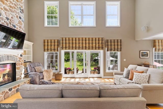 living area with plenty of natural light, a high ceiling, a fireplace, and wood finished floors