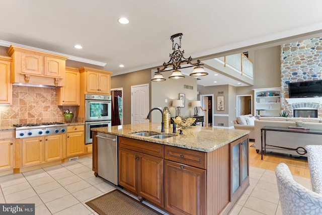 kitchen with light tile patterned flooring, a sink, an island with sink, stainless steel appliances, and decorative backsplash