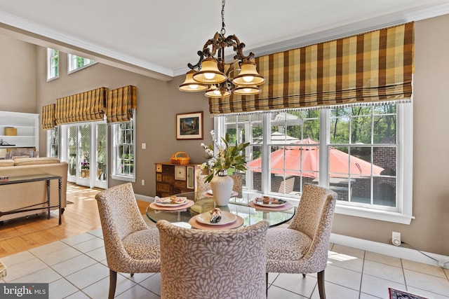 dining space with an inviting chandelier, light tile patterned floors, ornamental molding, and baseboards
