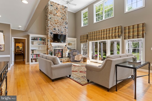 living area featuring light wood-type flooring, ornamental molding, baseboards, and a towering ceiling