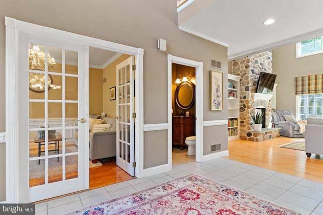interior space featuring crown molding, tile patterned flooring, visible vents, a fireplace, and a chandelier