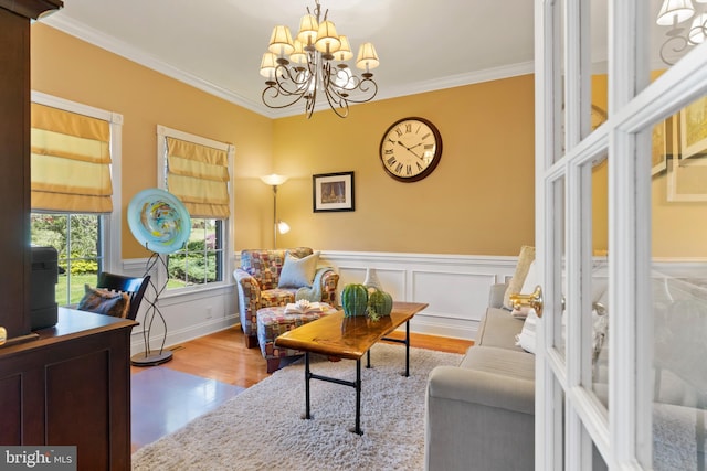 sitting room featuring wainscoting, an inviting chandelier, ornamental molding, and wood finished floors