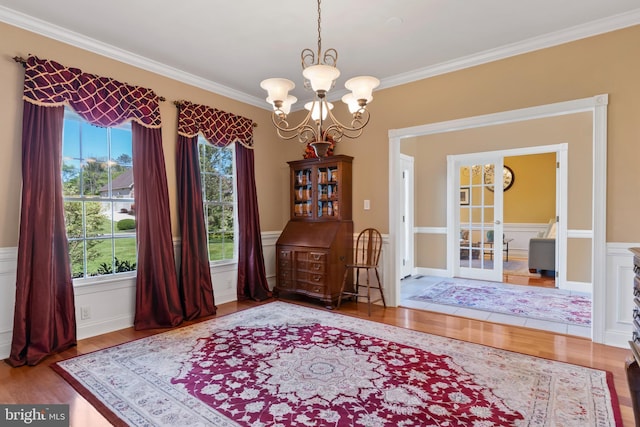 dining room with an inviting chandelier, ornamental molding, wood finished floors, and french doors