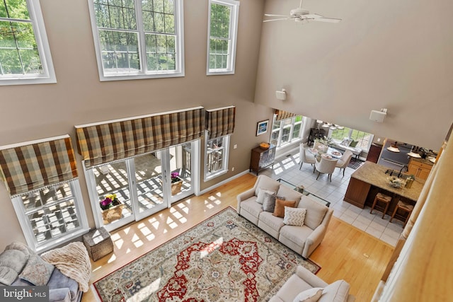 living room with a ceiling fan, a high ceiling, and wood finished floors