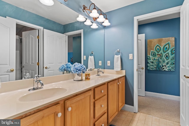 bathroom with double vanity, a sink, baseboards, and tile patterned flooring
