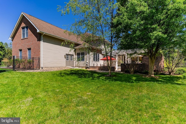 back of property with brick siding, fence, and a yard