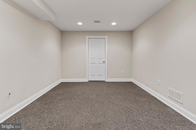 unfurnished room with baseboards, dark carpet, and visible vents