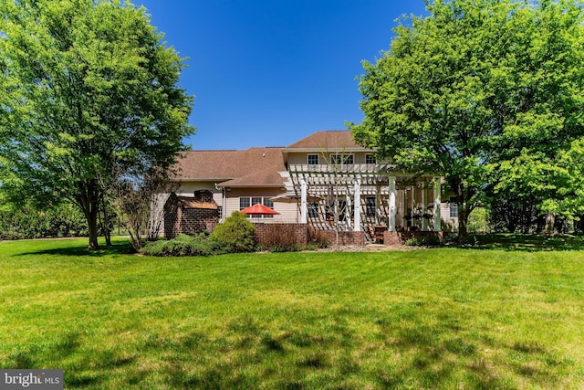 rear view of property featuring a yard and a pergola