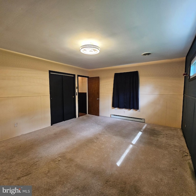 unfurnished bedroom with a baseboard heating unit and carpet