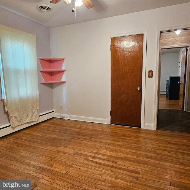 unfurnished bedroom featuring wood finished floors, baseboards, and baseboard heating