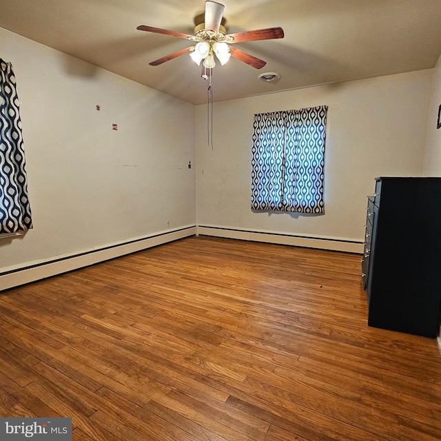 spare room with a ceiling fan, wood finished floors, and baseboards