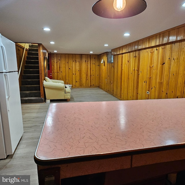kitchen with freestanding refrigerator, wood finished floors, recessed lighting, and wood walls
