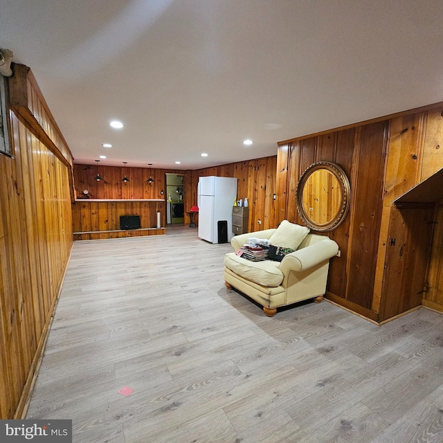 sitting room with light wood-type flooring, wood walls, recessed lighting, and baseboards