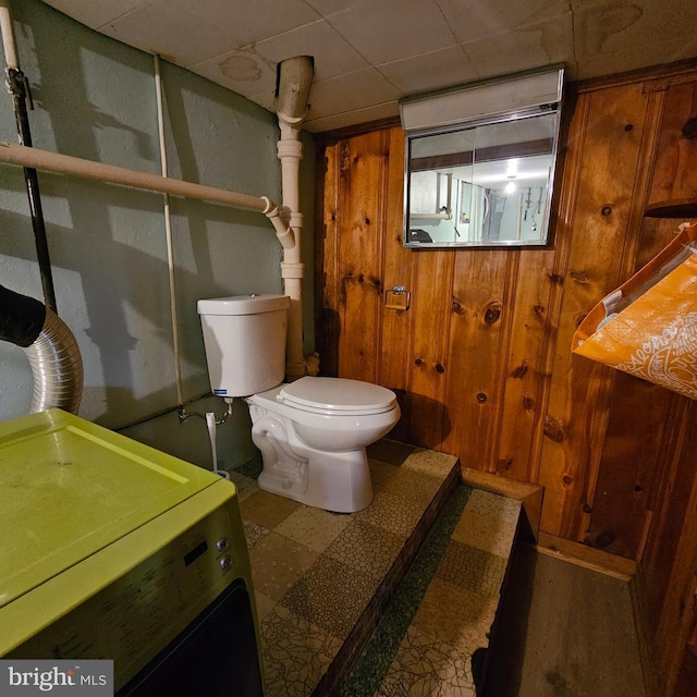 bathroom with washer / clothes dryer, toilet, wooden walls, tile patterned floors, and vanity