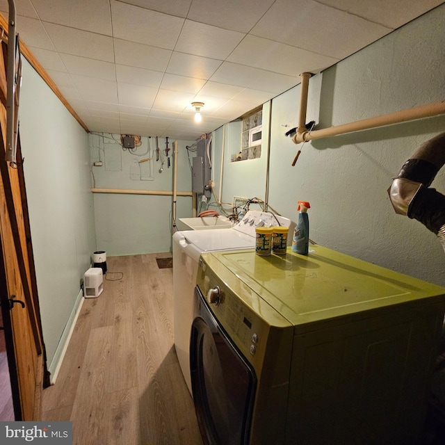 clothes washing area featuring separate washer and dryer, light wood finished floors, and electric panel