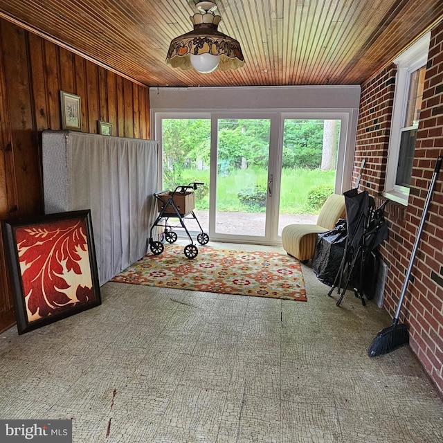 sunroom featuring healthy amount of natural light, carpet, wooden ceiling, brick wall, and wood walls