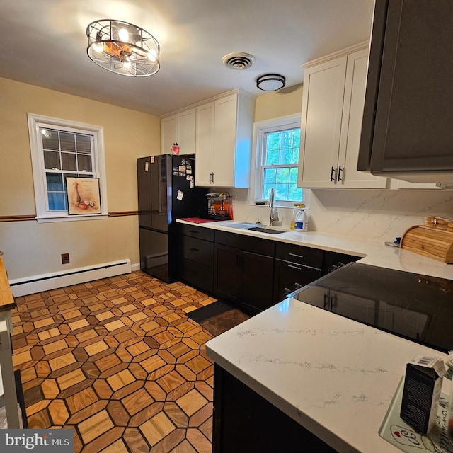 kitchen with a baseboard heating unit, a sink, white cabinetry, freestanding refrigerator, and dark cabinets