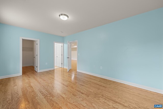 6348 Flintstone Dr, Barboursville, VA 22923 - unfurnished bedroom with a walk in closet, baseboards, a closet, and light wood finished floors