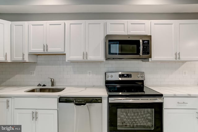 kitchen featuring a sink, stainless steel appliances, decorative backsplash, and white cabinets