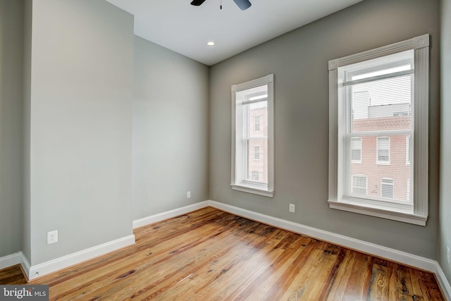 spare room with ceiling fan, hardwood / wood-style flooring, and baseboards
