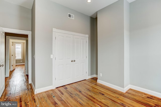 unfurnished bedroom featuring a closet, light wood-type flooring, visible vents, baseboards, and recessed lighting