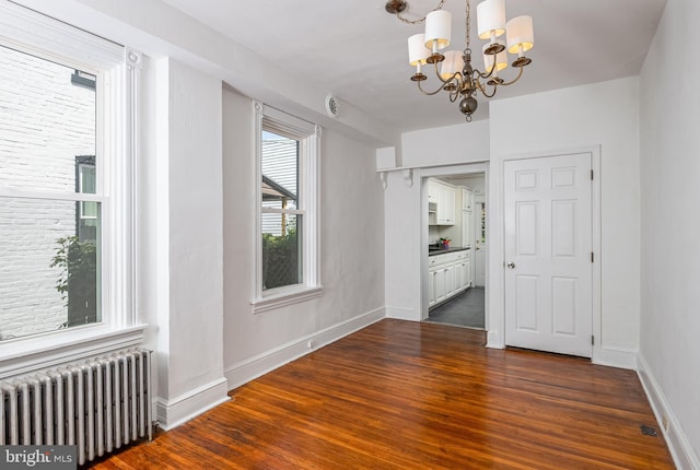 unfurnished dining area with an inviting chandelier, dark wood-style flooring, radiator heating unit, and baseboards