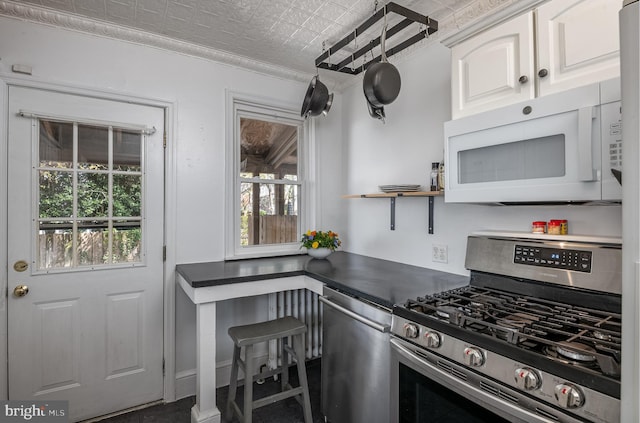 kitchen with an ornate ceiling, ornamental molding, dark countertops, white cabinets, and appliances with stainless steel finishes