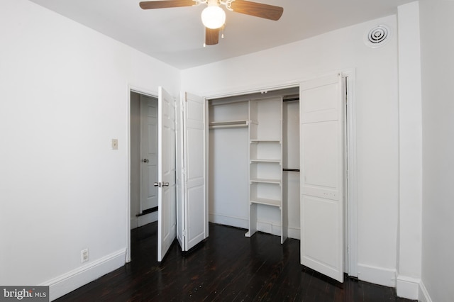 unfurnished bedroom with a closet, ceiling fan, baseboards, and dark wood-type flooring