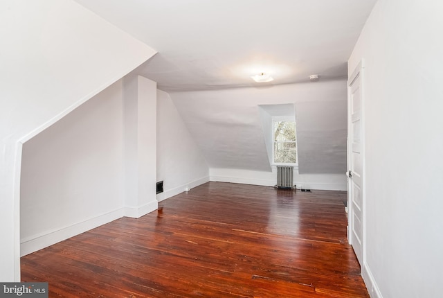 additional living space featuring lofted ceiling, visible vents, baseboards, wood-type flooring, and radiator heating unit