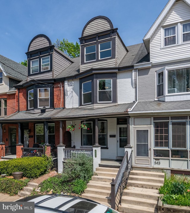 townhome / multi-family property with a porch and brick siding