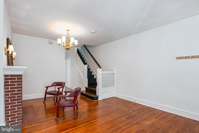 sitting room with an inviting chandelier, wood finished floors, baseboards, and stairs