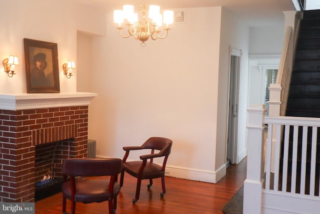 sitting room featuring a chandelier, a brick fireplace, stairs, baseboards, and wood finished floors