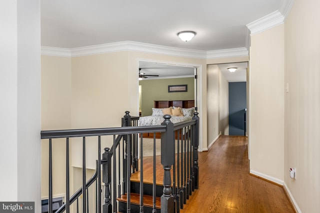 hall with baseboards, ornamental molding, wood finished floors, and an upstairs landing
