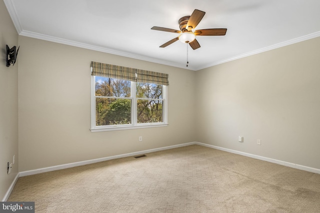 spare room with visible vents, crown molding, baseboards, a ceiling fan, and carpet