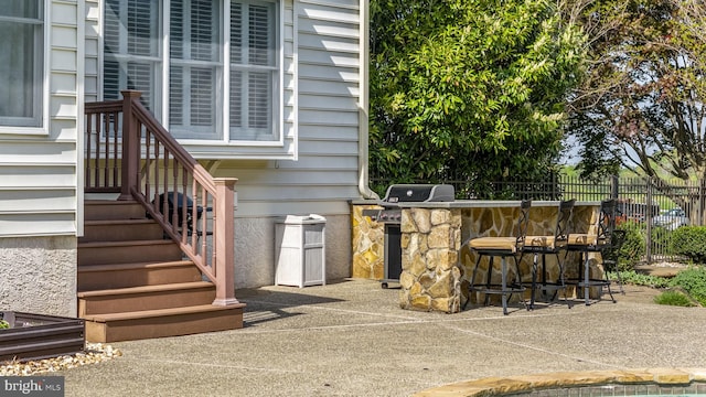 exterior space with fence, outdoor dry bar, and a grill