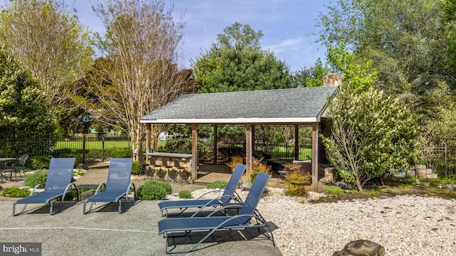 view of patio featuring fence, outdoor dry bar, and a gazebo